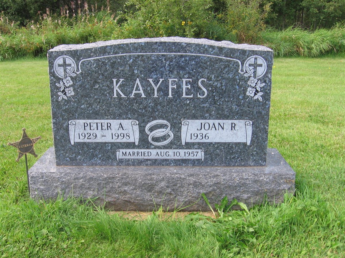 A traditional companion headstone in blue-gray granite with cross emblems, wedding rings and a scroll design.