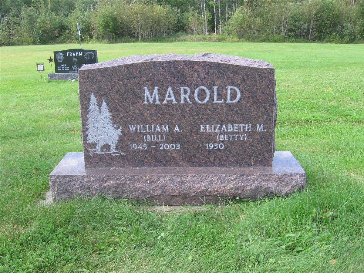 A traditional red granite headstone with a pine tree and deer engraving on a polished base.