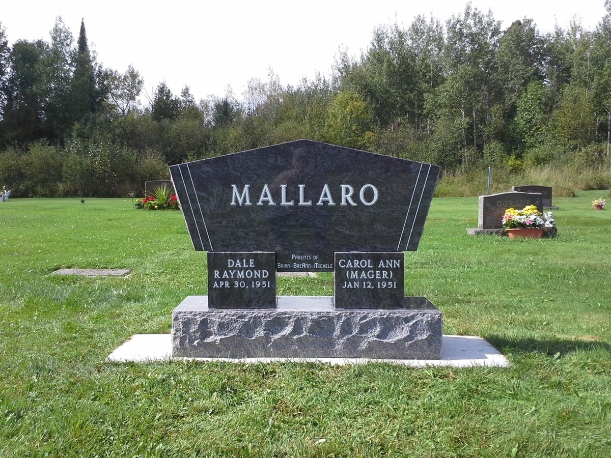 A black granite cremation urn monument with an angled top, two name tablets, and a rough-cut base.