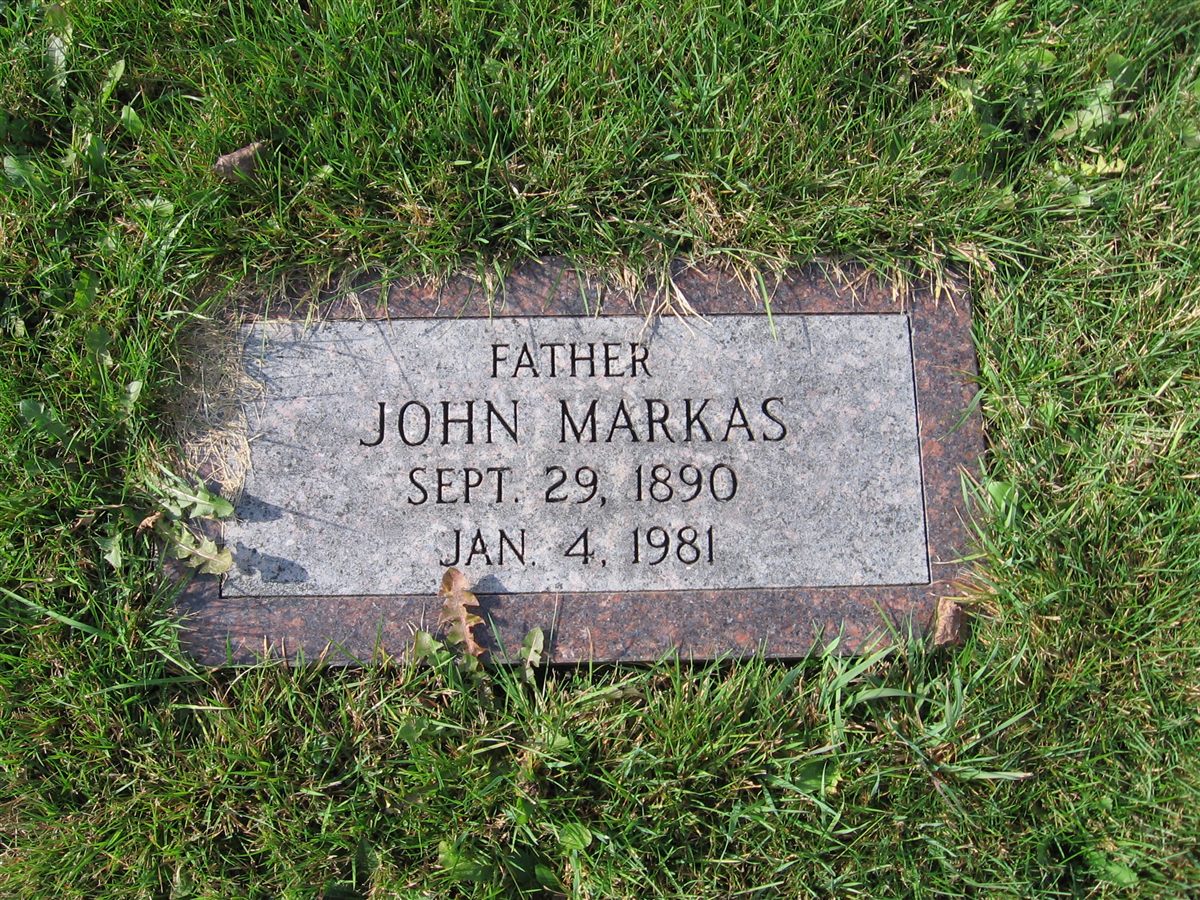 The Markas family marker before Grave Saver: flush with the lawn, no border, edges lost in the grass.